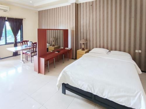 a bedroom with a large bed and a desk and a table at Gita Puri RedPartner Blitar in Blitar