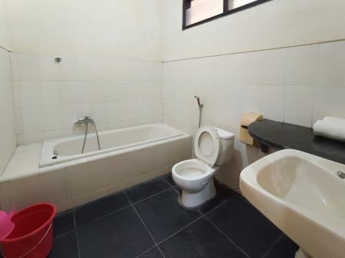 a bathroom with a toilet and a tub and a sink at Gita Puri RedPartner Blitar in Blitar