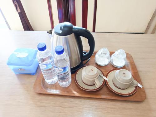a tray with cups and water bottles on a table at Gita Puri RedPartner Blitar in Blitar