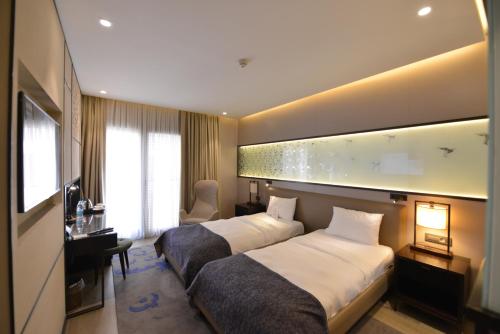 a hotel room with two beds and a television at Waxwing Hotel in Hatay