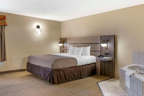 a hotel room with a large bed and a tub at Quality Inn Raleigh Downtown in Raleigh