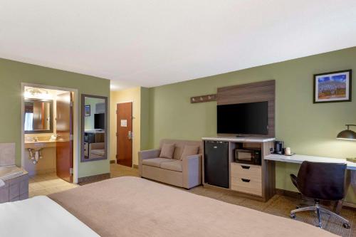 a hotel room with a bed and a desk with a television at Quality Inn Raleigh Downtown in Raleigh