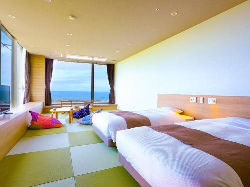 a bedroom with four beds and a view of the ocean at Ooedo Onsen Monogatari Premium Shiomiso in Murakami