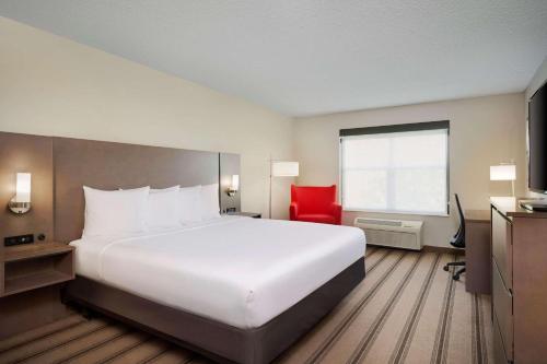 a hotel room with a large white bed and a red chair at Country Inn & Suites by Radisson Albertville near Outlet Mall in Albertville