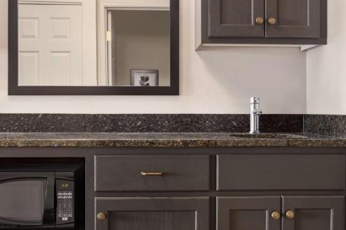 a kitchen counter with a sink and a mirror at Country Inn & Suites by Radisson, St Cloud East, MN in Saint Cloud