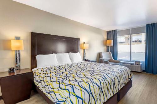 a hotel room with a bed and a chair and a window at Rodeway Inn in Orange Park