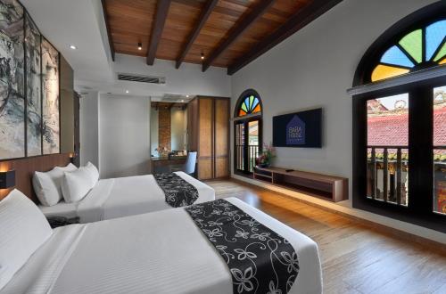 two beds in a room with two windows at Baba House Melaka in Melaka