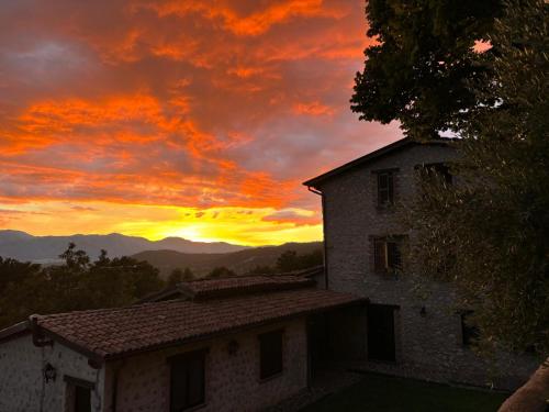 a sunset over a house with a building at Casale La Quercia in Poggio Bustone