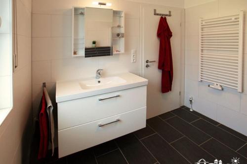Un baño blanco con lavabo y espejo. en 42 Ferienwohnung im Birkenweg 1c EG, en Burg auf Fehmarn