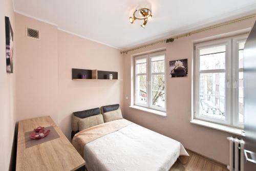 グダニスクにあるGdańskie Apartamenty - Apartament Szeroka with 2 roomsのベッドとテーブルと窓のある寝室