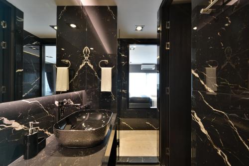 a black bathroom with a sink and a mirror at Victora Hostel in Bangkok