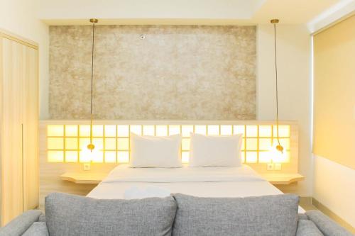 a bedroom with a bed and a couch at Modern and Spacious Studio Apartment at Mustika Golf Residence By Travelio in Cikarang