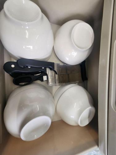 un tiroir rempli de bols blancs et d'un couteau dans l'établissement Sandakan Corner Terrace House, à Sandakan