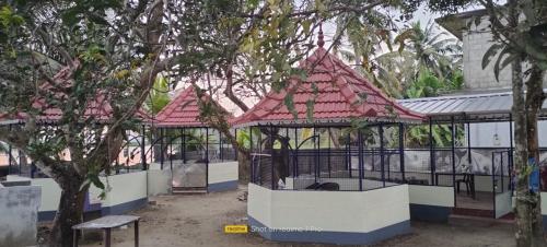 two gazebos with red roofs in a park at Cruise 'N Lake in Kumarakom