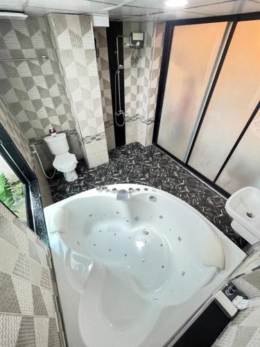 a large bath tub in a bathroom with a toilet at Sweetloft Hotel Don Muang in Bangkok