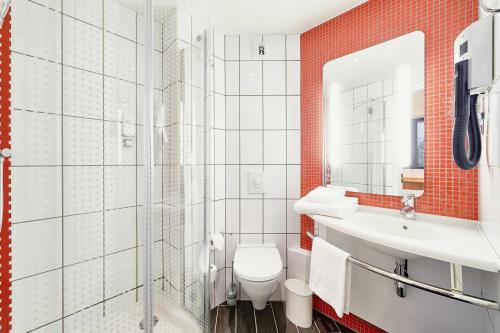 a bathroom with a toilet, sink and mirror at Ibis Krasnoyarsk Center in Krasnoyarsk