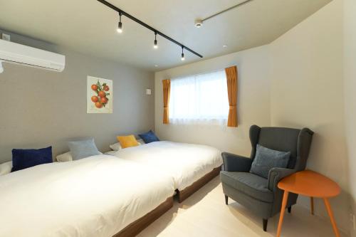 a bedroom with two beds and a chair at River Residence BOTAN by Tranova in Tokyo