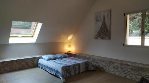 a bedroom with a bed and two windows at Gîte Jet d'eau avec piscine intérieure 30 minutes Versailles in Montainville