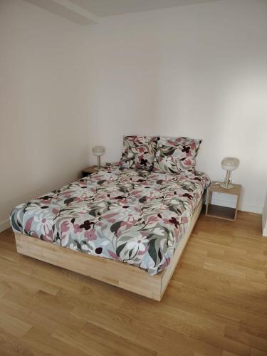 Ce lit se trouve dans une chambre blanche dotée d'un couvre-lit avec des fleurs. dans l'établissement Grand appartement familial paris13, à Paris