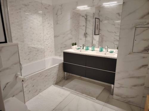 une salle de bain avec un lavabo, une baignoire et un miroir dans l'établissement Grand appartement familial paris13, à Paris