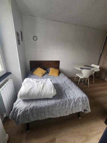 Cette chambre comprend un lit avec des oreillers jaunes et un bureau. dans l'établissement Loft cosy au calme, à Montbéliard