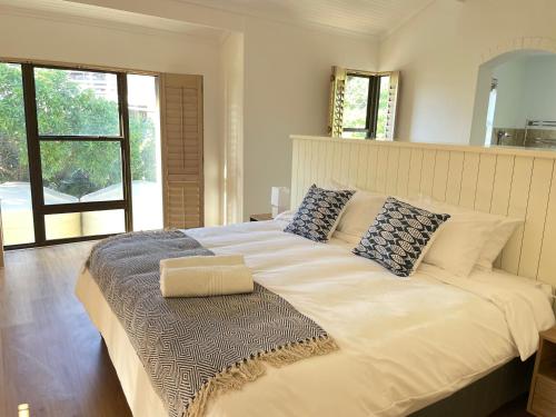 Una cama blanca grande en una habitación con ventana. en Ocean Mooring Beach Apartment " no sea view, 50m from beach", en Port Alfred