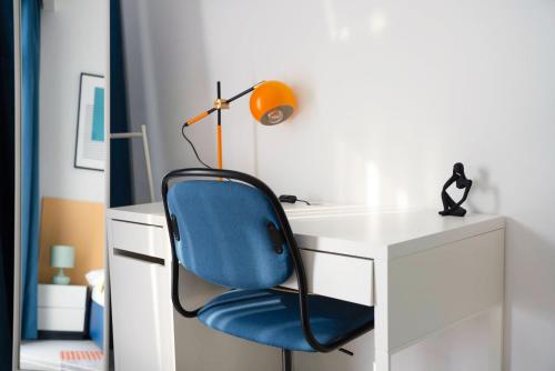 a blue chair sitting in front of a white desk at Izzzi Life Mint in Dubai