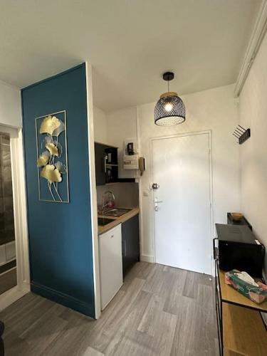une petite cuisine avec un mur bleu et une porte dans l'établissement Studio calme proche de Lyon avec parking privé, à La Mulatière