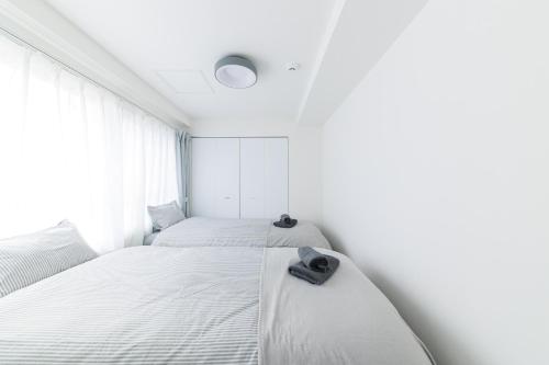 two beds in a room with white walls and a window at Ruby in Otaru