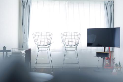 a living room with three chairs and a flat screen tv at Ruby in Otaru