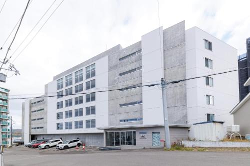 a white building with cars parked in a parking lot at Ruby in Otaru