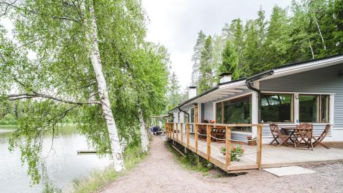 a house with a deck next to a body of water at Lakeside Villa next to Nuuksio National Park, in addition Hot Tub and Breakfast in Otalampi