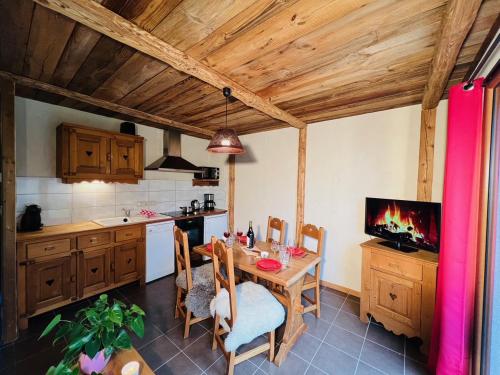 a kitchen with a table and a tv in it at Nordique Symbiose in Chapelle-des-Bois