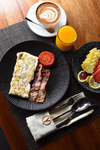 Un plato negro con huevos, tocino y queso y una taza de café. en Yushili Hotel Kampala, en Kampala