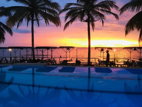 a resort swimming pool with a sunset in the background at New Saniro Lagoon Deck in Katunayaka