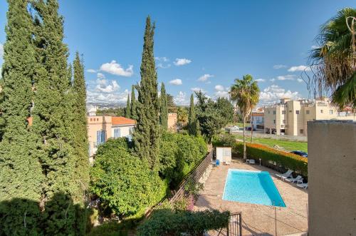 a swimming pool in a garden with trees and buildings at Private Room in shared apartment in Paphos