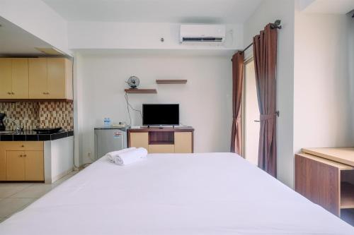 une chambre avec un grand lit blanc et une cuisine dans l'établissement Comfort Living Studio at Margonda Residence 5 Apartment By Travelio, à Depok