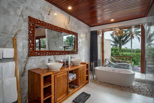 a bathroom with two sinks and a tub and a mirror at Dewi Kunti Villa in Tegalalang