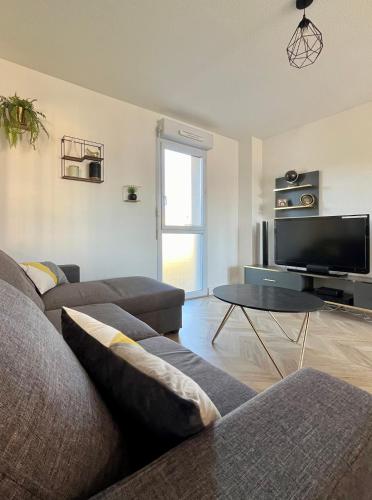 un salon avec un canapé et une télévision dans l'établissement Narb'home, Cosy , Parking, Balcon, à Narbonne