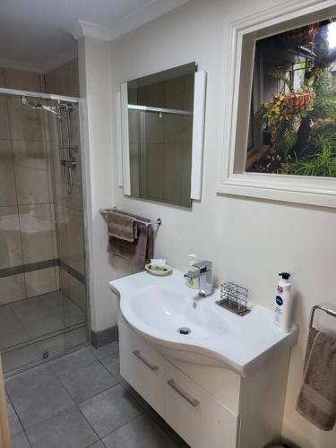 a white bathroom with a sink and a shower at Apartment on Mica in Broken Hill
