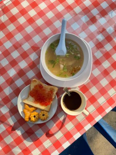 a bowl of soup and a plate of toast and a cup of coffee at Rang Noknoy Resort at Kohlarn in Ko Larn
