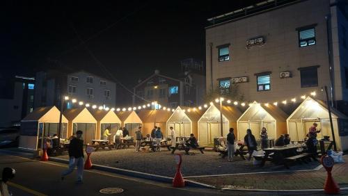 a group of people standing around a group of white tents at Daecheon sagwanamu pension in Boryeong