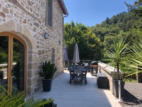 a patio with tables and umbrellas next to a building at Gîte Val Souvigne in Saint-Sylvain