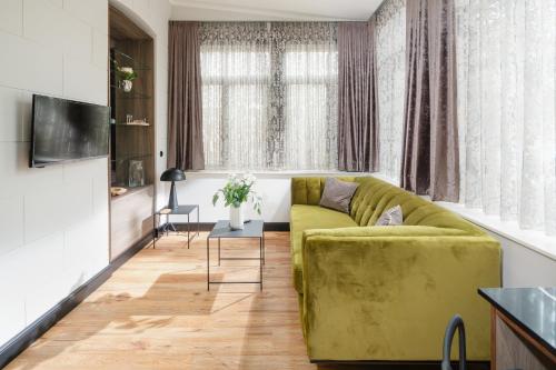 a living room with a green couch and a table at Juweel Huus 1 I 99m Strand I Terrasse I Strandkorb I 99m Kurplatz I by Wooon in Norderney
