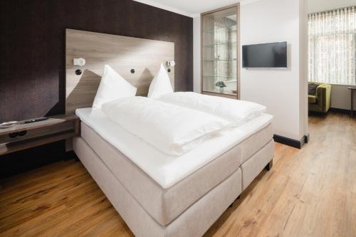 a large white bed in a room with a television at Juweel Huus 1 I 99m Strand I Terrasse I Strandkorb I 99m Kurplatz I by Wooon in Norderney