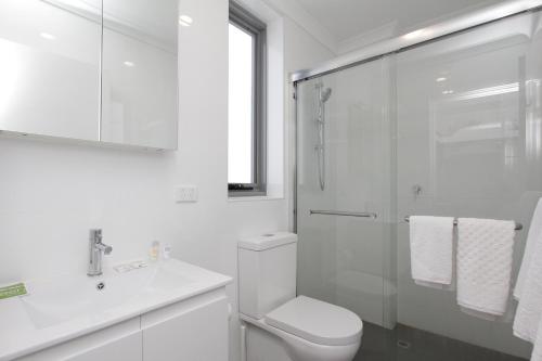 a white bathroom with a toilet and a shower at 188 Apartments in Perth