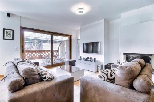 a living room with two leather couches and a fireplace at Lodge 6, Next To Cable Car in Champéry