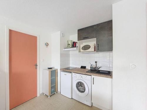 une cuisine avec un lave-linge et un micro-ondes dans l'établissement S-Lac 03-Soutons Appartement 4 personnes dans résidence au bord du lac marin, à Soustons