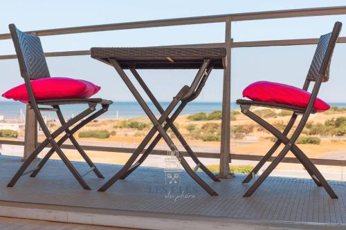 - deux chaises avec des oreillers rouges assises sur un balcon dans l'établissement Le Grand Large Studio face mer, à Le Touquet-Paris-Plage