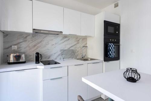 une cuisine avec des placards blancs et un comptoir blanc dans l'établissement Beautiful flat with balcony - 200m from the beach, à Antibes